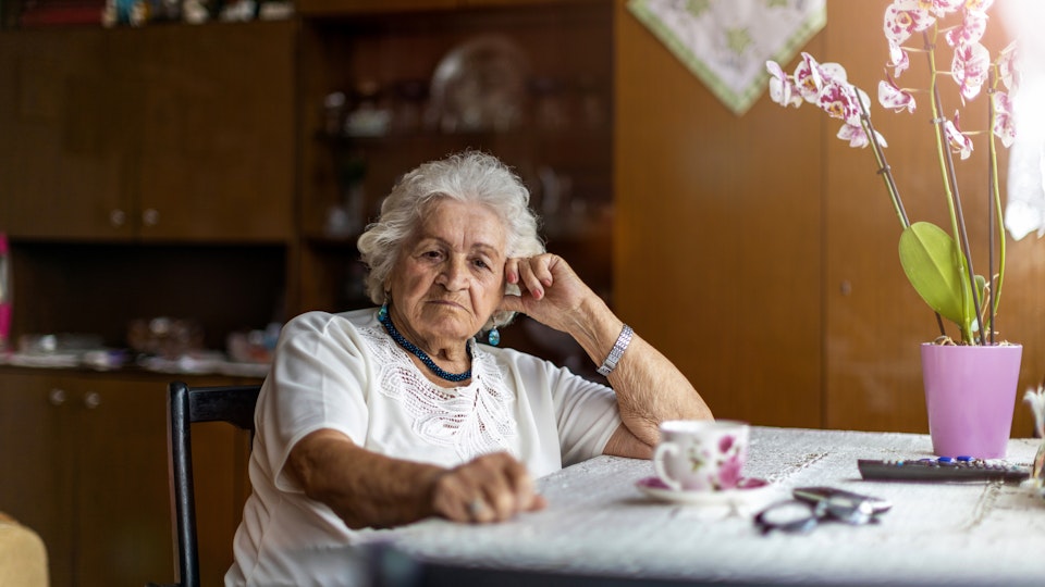 Older woman sitting at kitchen table.